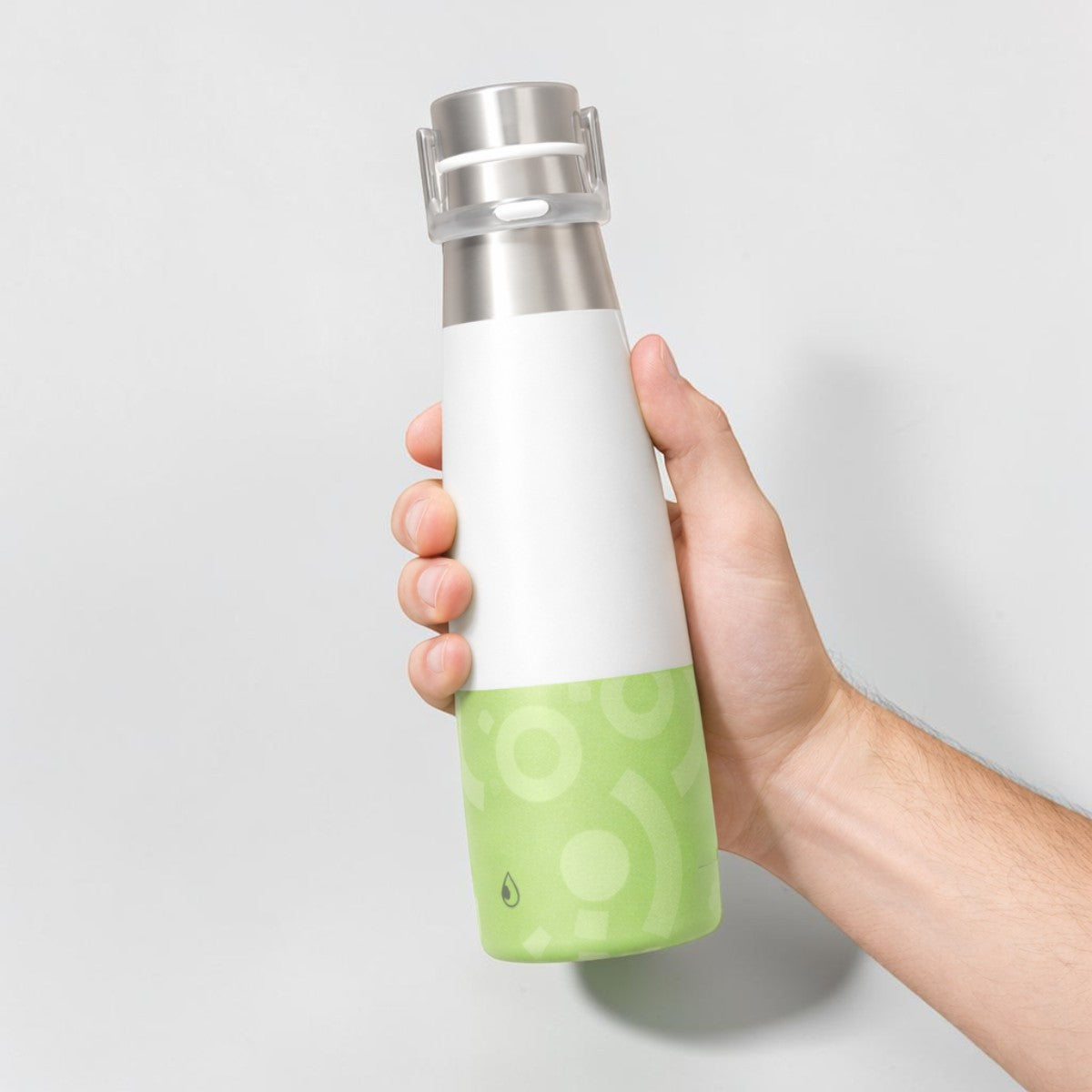 Stockka slim white and green stainless steel water bottle with metal cap, held in hand.