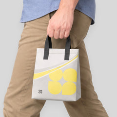 Stockka small grey non-woven polypropylene tote bag with yellow floral design and black handles, ideal for daily use.