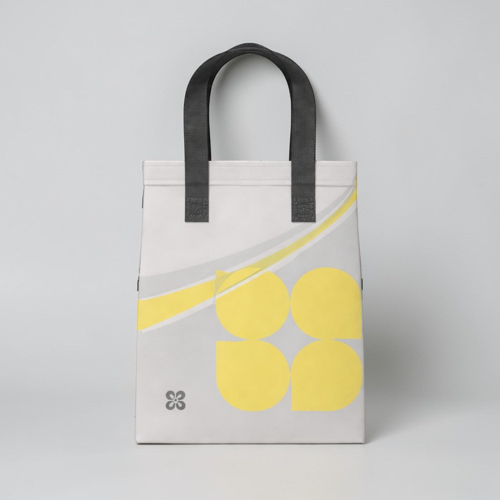 Stockka small grey non-woven polypropylene tote bag with yellow abstract design and black handles, ideal for daily use.