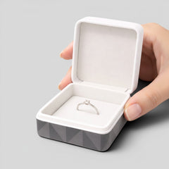 Stockka square jewelry box with hinged lid, soft white interior, and geometric grey exterior. Ideal for rings or necklaces.