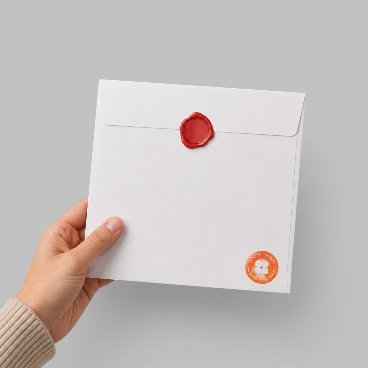 Stockka square white paper envelope with a red wax seal, held by a hand, perfect for formal invitations.