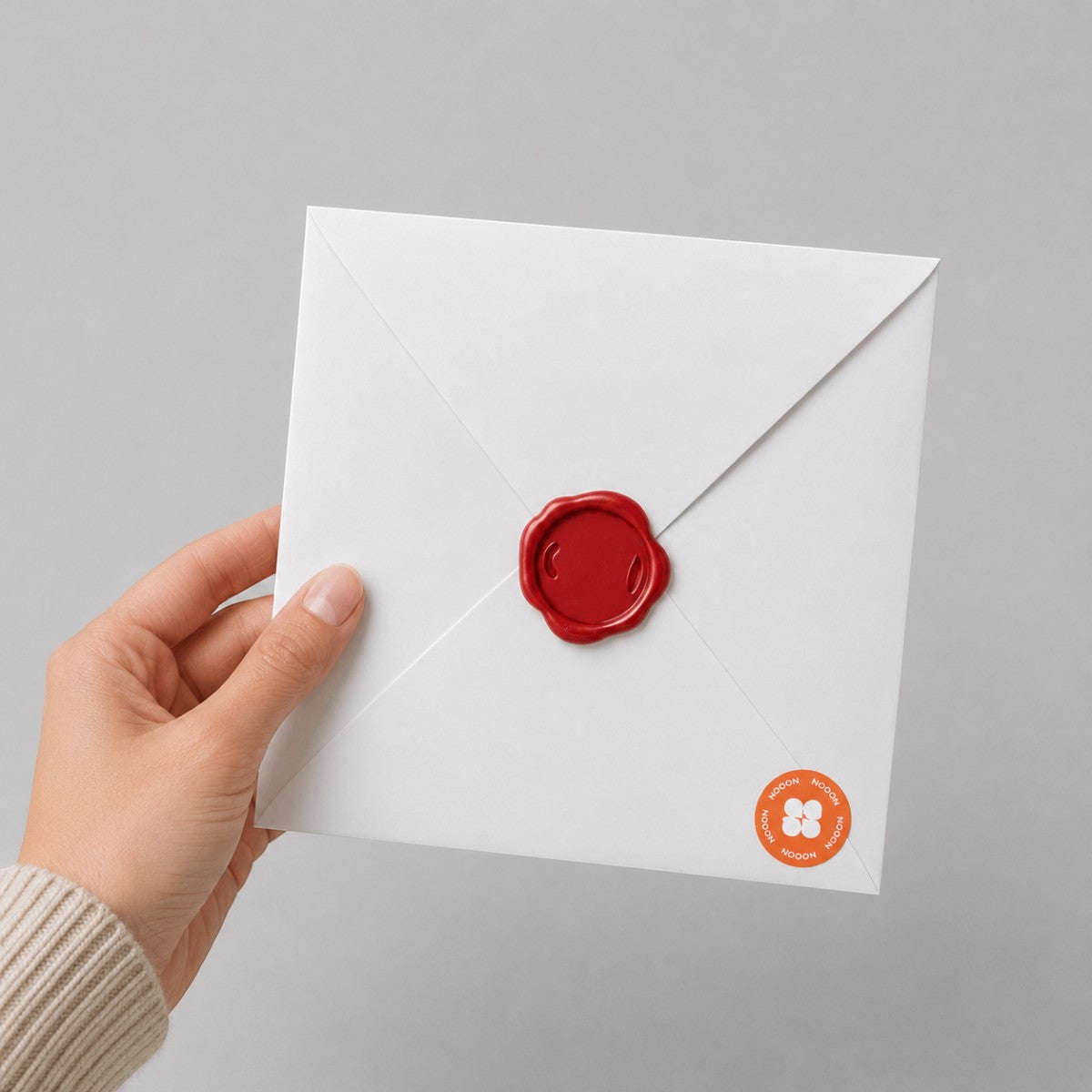 Stockka white square envelope with a red wax seal held by a hand, perfect for elegant wedding invitations.