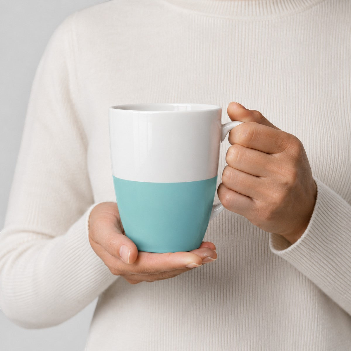 Stockka tall ceramic mug with a white and light blue two-tone design held in hands