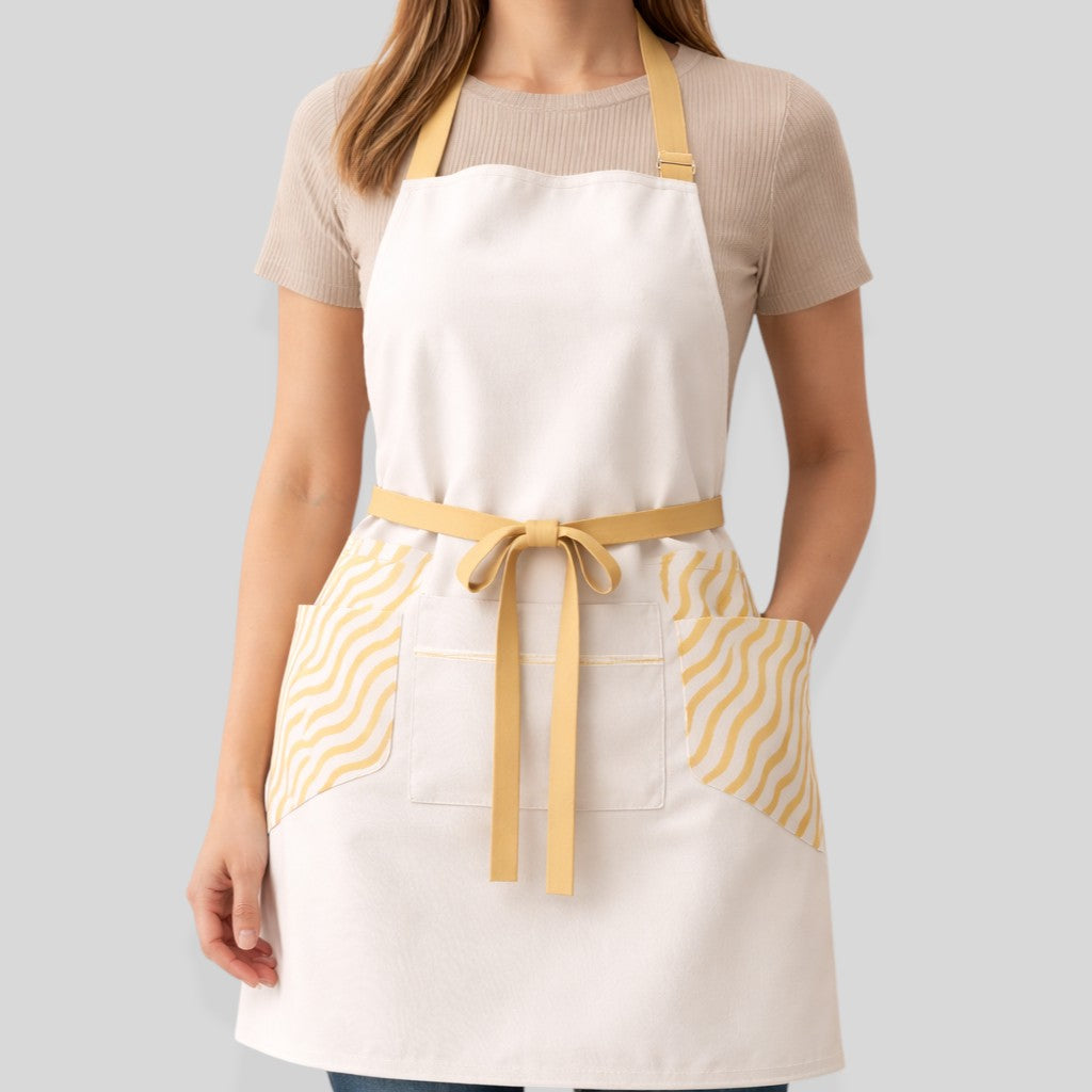 Stockka white full-length apron with yellow wave pattern side pockets and adjustable neck strap.