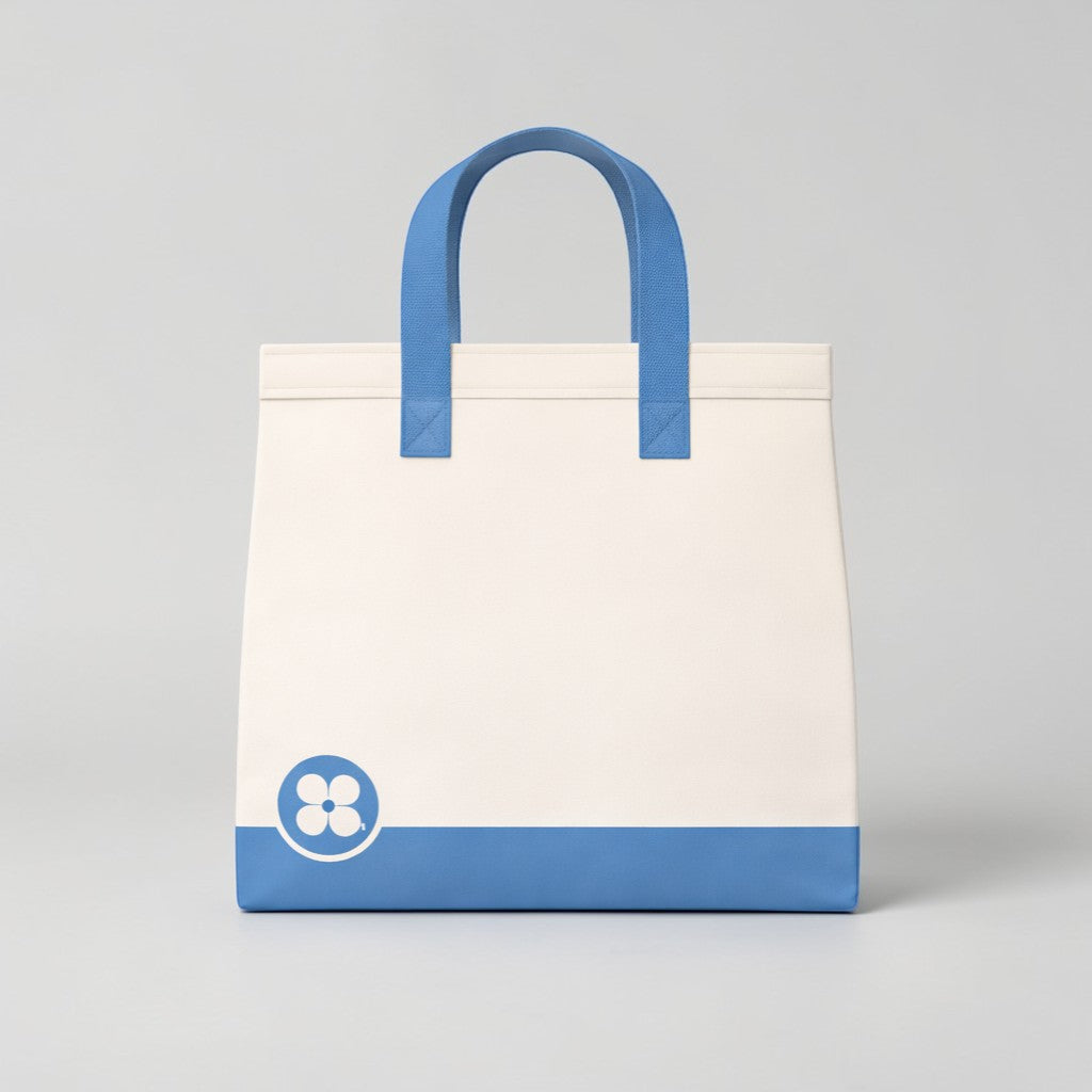 Stockka large white tote bag with blue handles and a blue base. Features a floral logo on the lower left.