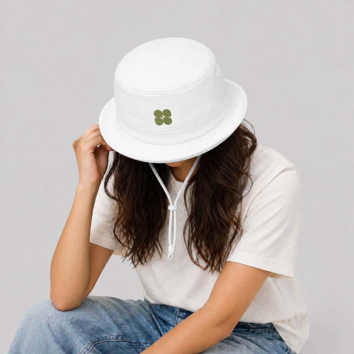 Stockka white cotton bucket hat with green clover detail and adjustable chin strap, ideal for outdoor activities.