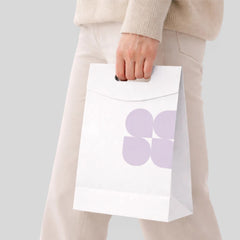 Stockka white kraft paper shopping bag with die-cut handle and a subtle purple floral design. Perfect for retail packaging.