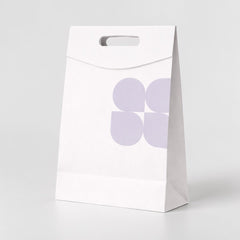 Stockka white kraft paper shopping bag with die-cut handle and subtle purple floral pattern. Ideal for retail packaging.