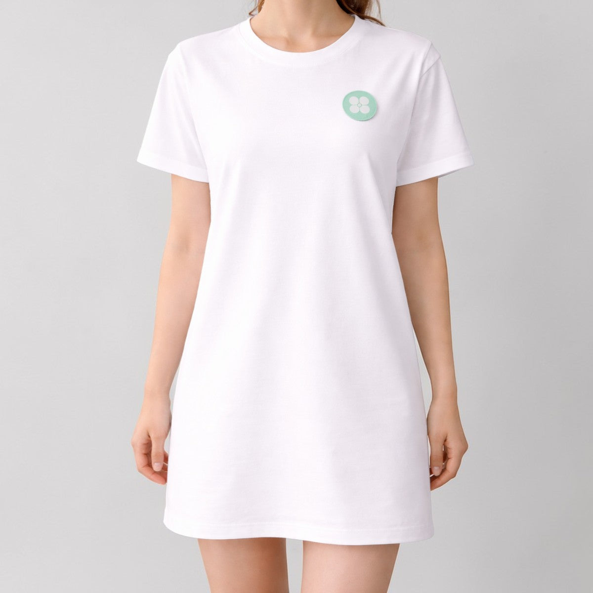 Stockka white 100% cotton oversized t-shirt dress with round neckline and short sleeves, featuring a small mint green circular logo on the chest.