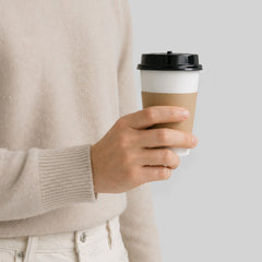 Stockka white paper cup with black lid and brown kraft sleeve, ideal for hot beverages like latte or tea.