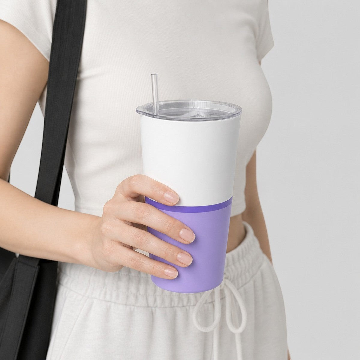 Stockka white and purple double-walled stainless steel tumbler with metal straw and clear lid, held by a woman.