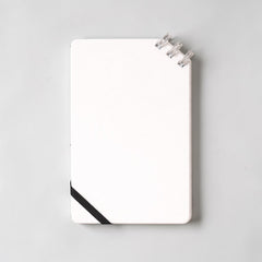 Stockka compact white spiral notebook with black elastic closure and 80 lined pages.