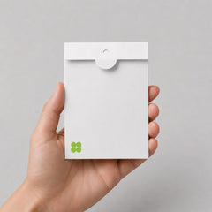 A hand holding a Stockka white matte 350g cardboard envelope with a circular thumb-lock closure for elegant invitations.