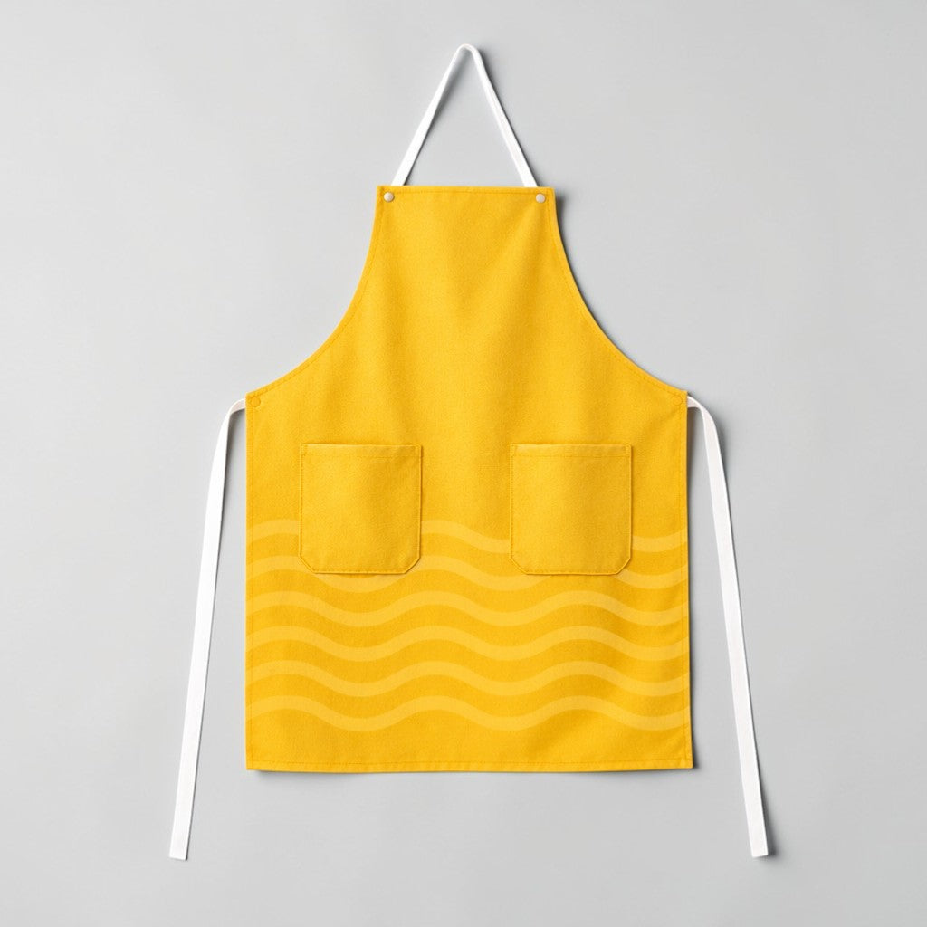 Stockka yellow full-length apron with three pockets and a subtle wave pattern. Made from a cotton-polyester blend.