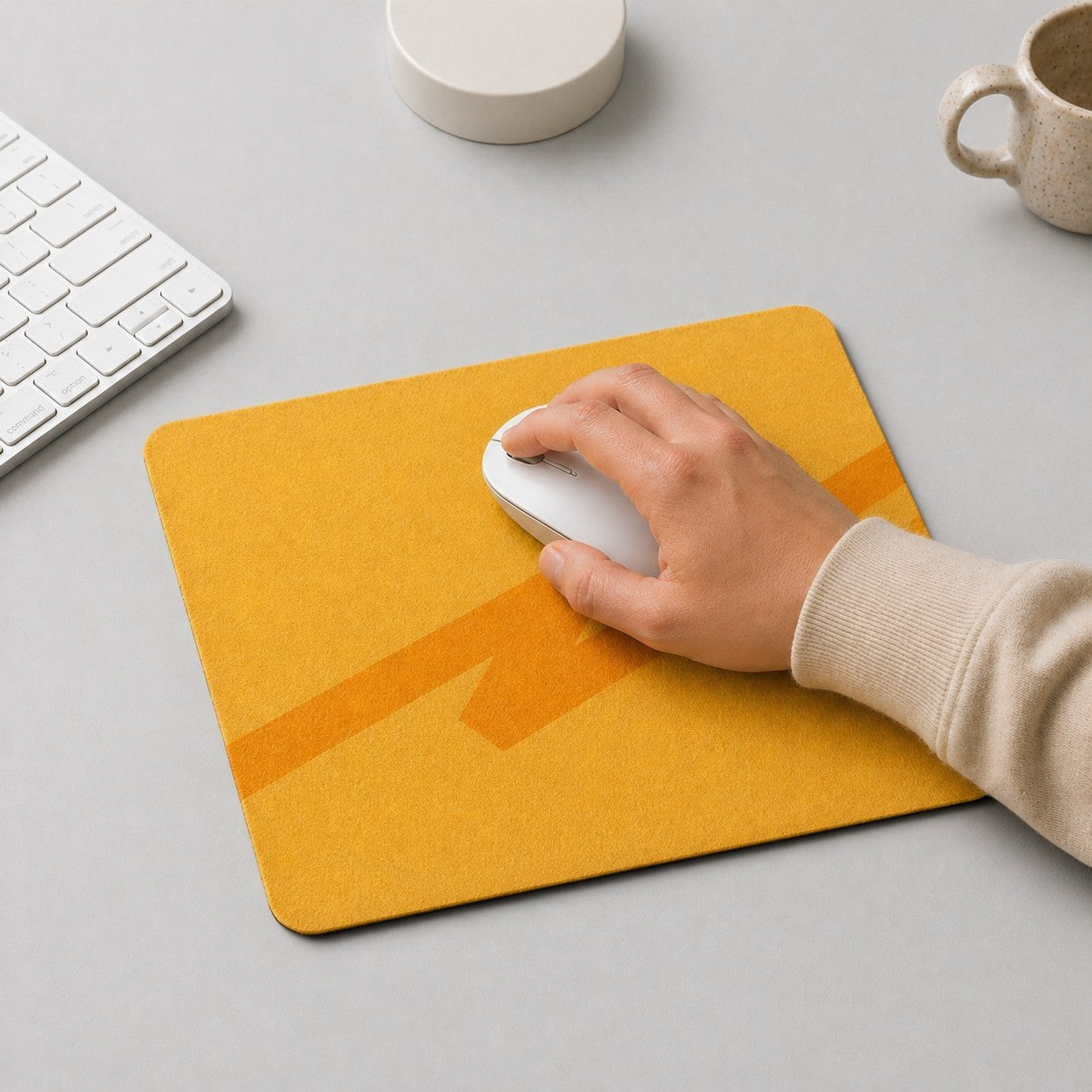 Stockka yellow felt mouse pad with orange geometric design. A hand uses a white mouse on the pad.