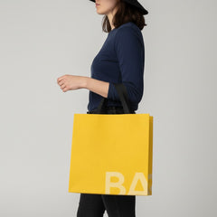 Stockka yellow laminated non-woven tote bag with black handles and subtle logo detail.